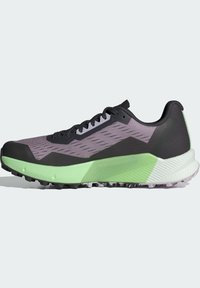 Scarpa sportiva nera e viola con tomaia in rete testurizzata, suola intermedia verde e suola nera robusta. Presenta lacci e dettagli stampati.