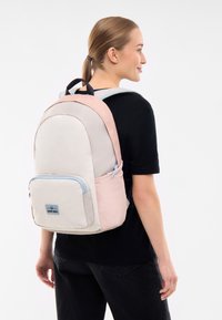 Könnyű, pasztell színű hátitáska: rózsaszín, bézs és világoskék. Párnázott pántokkal, elülső zsebbel és sima textúrával rendelkezik.