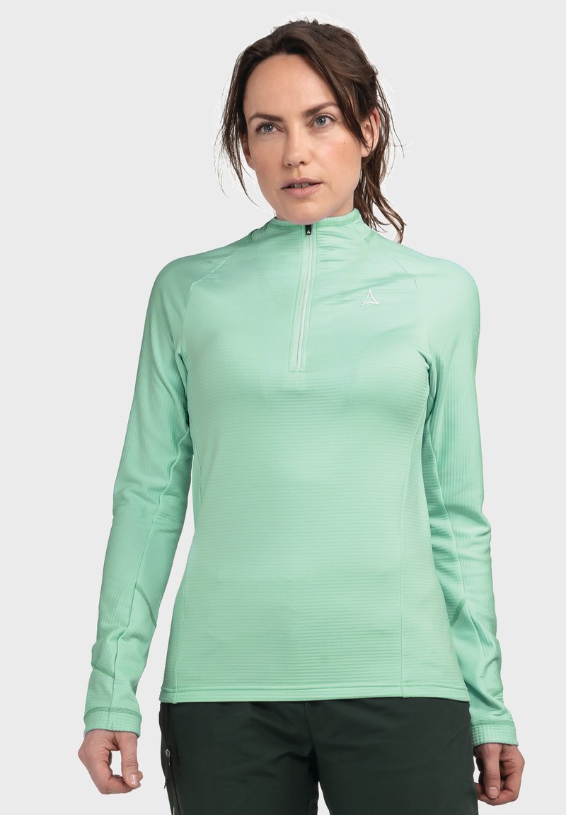 Helles grünes Langarmhemd mit halben Reißverschluss, aus strukturiertem Stoff. Verfügt über ein kleines Logo auf der Brust und taillierte Ärmel.