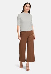 Jasnoszara bluzka z krótkim rękawem w połączeniu z brązowymi spodniami typu wide-leg, o prostym designie i gładkiej teksturze. Całość dopełniają sandałki na obcasie.