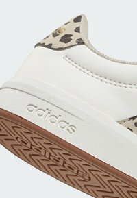 Bijela kožna tenisica s bež naglascima u leopardskom uzorku, gumenim potplatom i teksturiranim prihvatom. Na bočnoj strani nalazi se znak 'adidas'.