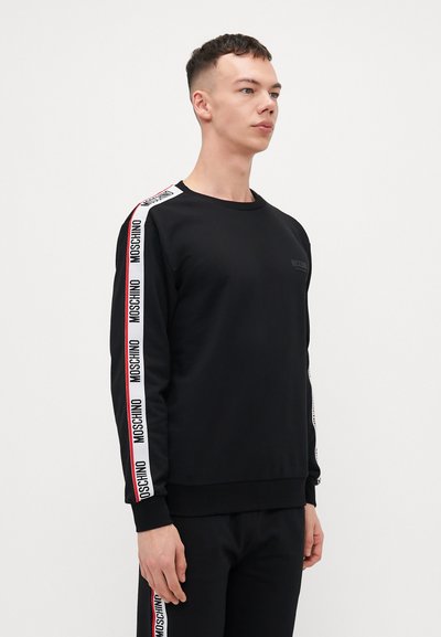 Sweatshirt noir à manches longues, col rond et accents de logo imprimés le long des manches. Fabriqué en tissu lisse avec une coupe ajustée.
