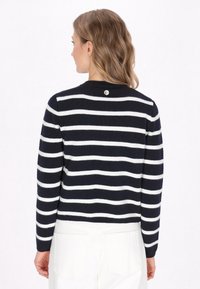 Maglione a righe blu navy e bianche con scollatura a girocollo, maniche lunghe e dettaglio con bottone logo in tono argento sul retro. Texture a maglia morbida.