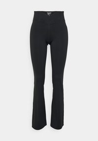 Czarne legginsy w stylu dzwonów z wysokim stanem. Charakteryzują się gładką teksturą oraz dopasowanym krojem. Szczegóły przeszycia podkreślają pas.