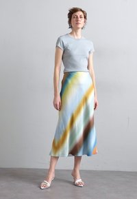 Blue ribbed short-sleeve top paired with a long, flowing skirt featuring diagonal, multicolored patterns in blue, yellow, and brown tones.