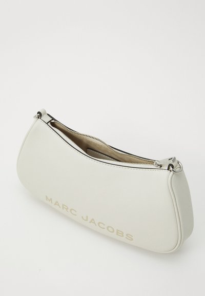 Balta ādas rokassoma ar izliekta dizaina, augšējo rāvējslēdzēja aizdari, iekšējo oderi un "MARC JACOBS" zīmolu zeltā vienā pusē.