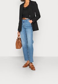 Černý blazer, černý krajkový top, světle modré džíny s vysokým pasem, hnědé kožené mokasíny a hnědá kabelka s malou rukojetí.