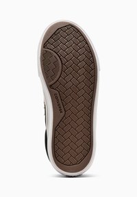 Semelle en caoutchouc brun d'une chaussure de sport avec un motif texturé, des côtés blancs et un accent de marque près du talon.