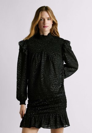 Abito nero con un colletto alto arricciato, maniche a sbuffo e tessuto testurizzato. Presenta arricciature all'orlo e una silhouette fluida.