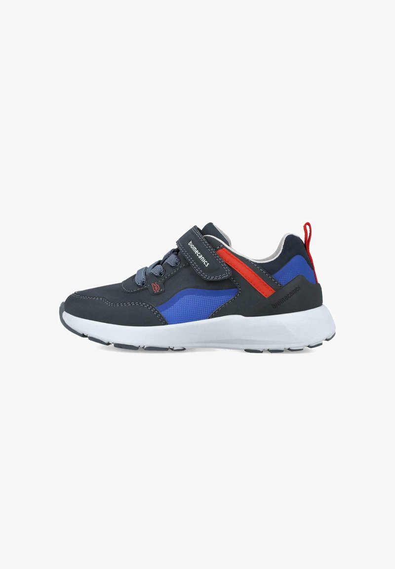 Zapatillas deportivas con upper de color gris oscuro, detalles en azul y acentos rojos. Cuenta con una correa de Velcro y paneles de malla texturizada. Suela blanca ligera.