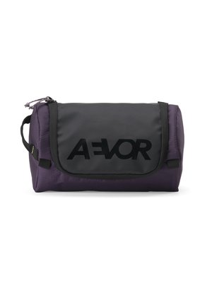 Kompatte schwarze und dunkelviolette AEVOR Kulturtasche mit Reißverschlussfächern und einem Griff auf einer Seite.