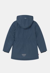 Tums zilas ārējā jaka ar kapuci, elastīgu jostasvietu, melniem piedurknēm un atstarojošiem elementiem aizmugurē. Gluda, ūdensizturīga auduma.