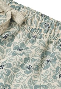 Tissu à motif floral en crème clair avec des fleurs bleu-vert. Comprend une taille élastique avec un lien en ruban texturé.