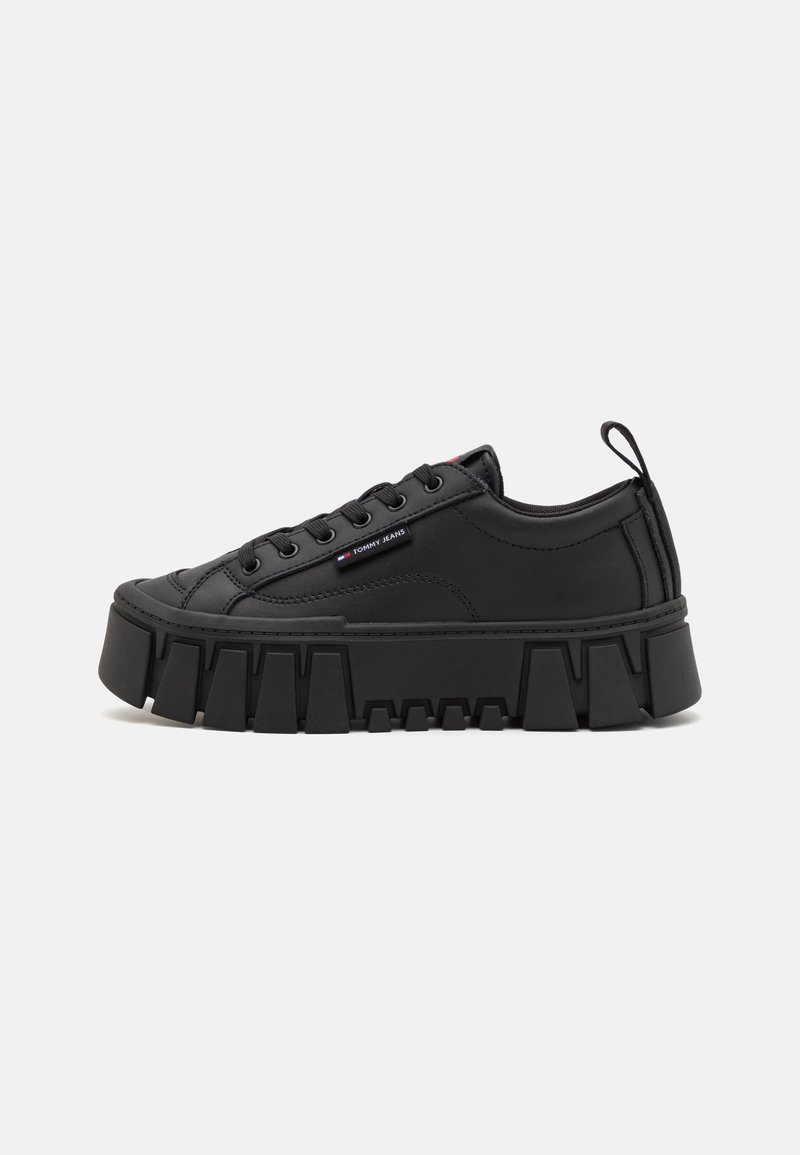 Baskets à plateforme noires avec semelle épaisse, lacets à l'avant, détails cousus et petit logo Tommy Jeans sur le côté sur fond uni.