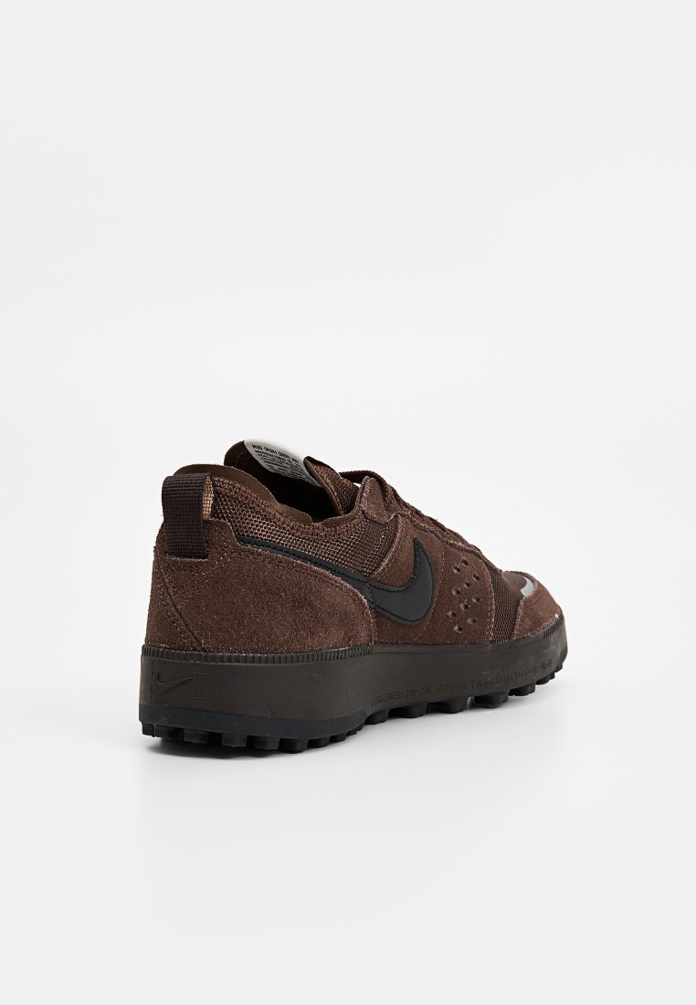 Sneakers en suède marron et mesh avec des accents noirs, dotées d'une semelle rembourrée, de détails texturés et d'une languette au niveau du talon.