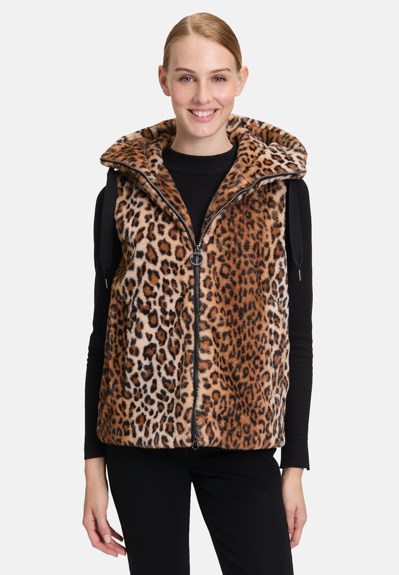 Kamizelka w panterkę z wysokim kołnierzem, wykonana z miękkiego sztucznego futra, z przednim zamkiem błyskawicznym i dwoma bocznymi kieszeniami. Paleta kolorów obejmuje odcienie brązu i beżu.