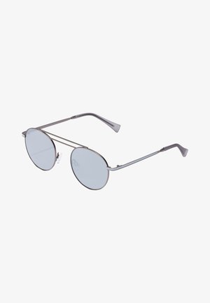 Okrągłe okulary przeciwsłoneczne z jasnoniebieskimi soczewkami, cienkimi metalowymi srebrnymi oprawkami oraz regulowanymi noskami. Charakteryzują się eleganckim, minimalistycznym designem.