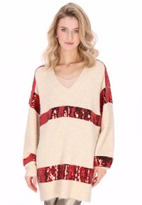 Maglione beige con strisce di paillettes rosse, design con scollo a V, maniche lunghe, tessuto a maglia strutturato e vestibilità ampia. Presenta un materiale morbido e peloso.