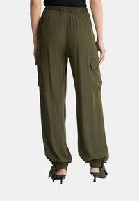 Pantalones cargo de color verde oliva con cintura elástica, bolsillos laterales y puños fruncidos, hechos de un tejido ligero y suave.