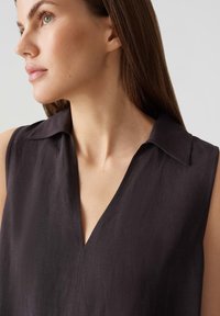 Donkere mouwloze blouse met een V-hals en kraag. Gemaakt van textiel met een structuur, met een subtiele glans en strakke lijnen.