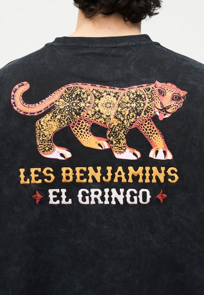 Μαύρο πουκάμισο με ένα στυλιζαρισμένο μεγάλο πορτοκαλί και μαύρο σχέδιο λεοπάρδαλης πάνω από το κείμενο "LES BENJAMINS EL GRINGO".