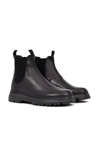 Botas Chelsea de cuero negro con paneles laterales elásticos, suelas de goma gruesas con dibujo y tiradores para ponerlas fácilmente. Textura suave, diseño elegante.
