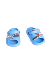 Blå plastträskor med utskurna sidor, med röda och svarta Hot Wheels-mönster; justerbar rem för säker passform; slät yta.