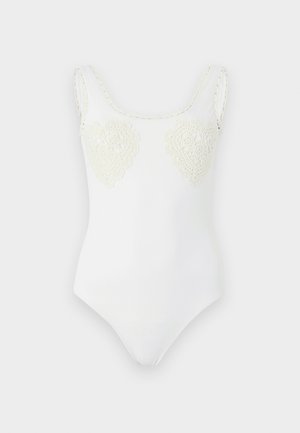 Λευκό αμάνικο κορμάκι με στρογγυλή λαιμόκοψη και δύο καρδιές από κεντημένη δαντέλα στο στήθος.