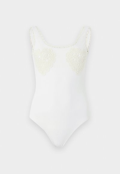 Λευκό αμάνικο κορμάκι με στρογγυλή λαιμόκοψη και δύο καρδιές από κεντημένη δαντέλα στο στήθος.