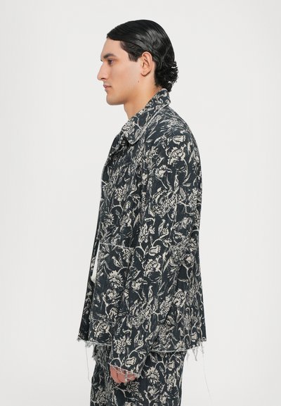 Jachetă din denim cu model floral, cu o bază de culoare albastru închis și un design alb. Prezintă o guler și o margine desfăcută, oferind un aspect texturat.