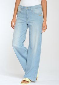 Světle modré, široké džíny vyrobené z denimu, se zapínáním na přední knoflík, několika kapsami a vybledlým vzhledem.