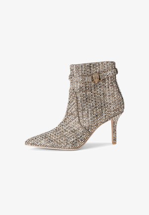 Hoge hak enkelboots met een spitse neus, versierd met een gestructureerd patroon van gouden en zilveren kralen en een gespdetail bij de enkel.