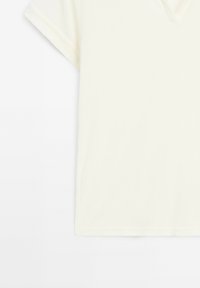 Tričko s krátkým rukávem a výstřihem do V v krémové barvě. Vyrobeno z jemné látky s hladkým povrchem. Jednoduchý design, žádné viditelné vzory nebo ozdobné prvky.