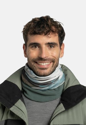 Cuello de multicolores hecho de tela elástica que presenta patrones abstractos. Se lleva sobre una camiseta gris y una chaqueta verde con un acento negro.