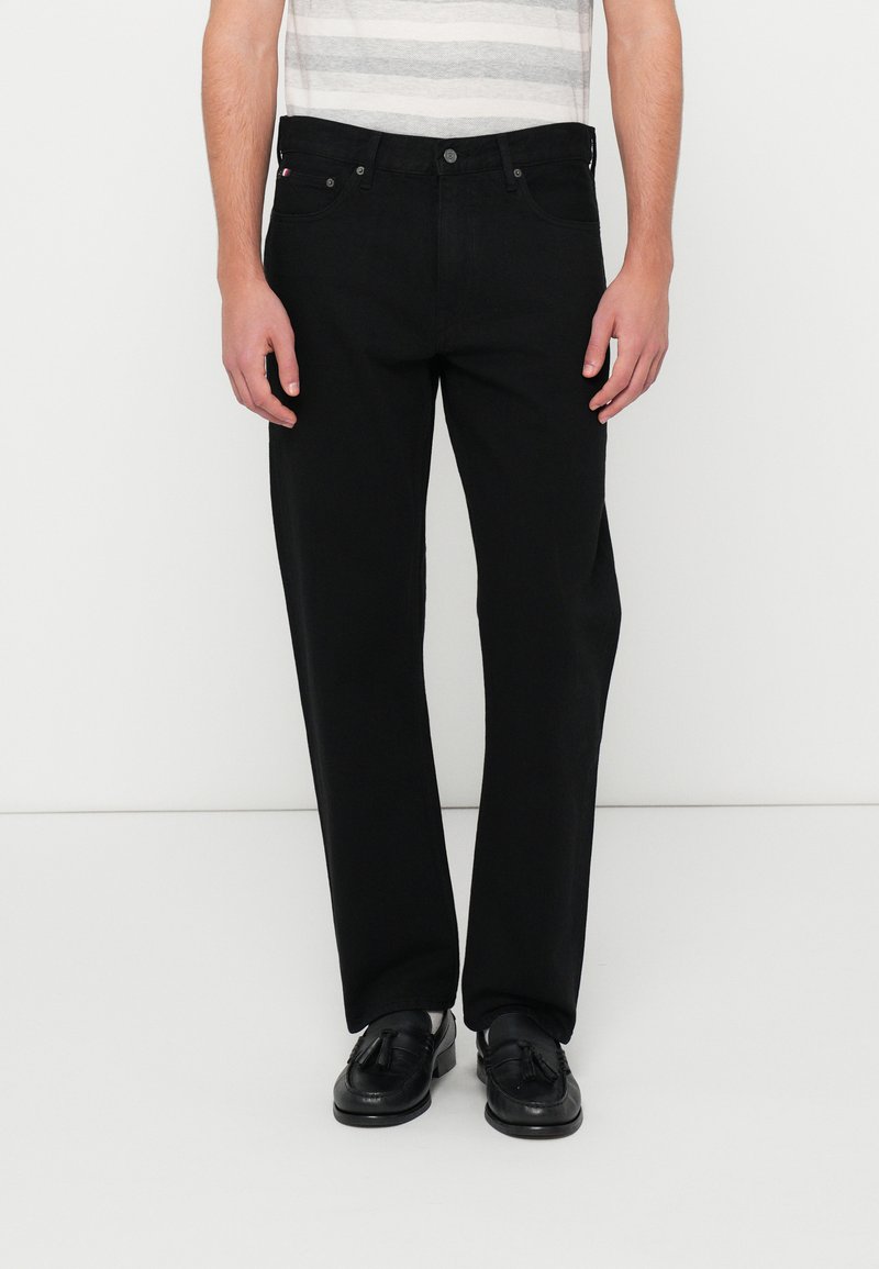 Jeans de mezclilla negra con un diseño de pierna recta, que cuentan con un cierre de botón, trabillas para cinturón y un estilo minimalista sin adornos.