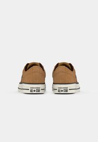 Brūni zamša sporta apavi ar augsto dizainu, baltiem gumijas zoles un melniem akcentiem. Raksturo "Converse All Star" zīmols uz papēža.