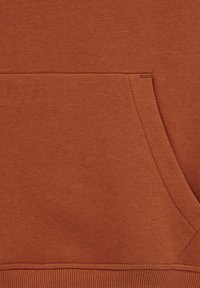 Tessuto della felpa color ruggine con una texture liscia. Presenta una tasca a marsupio e dettagli di orlo a coste. Design semplice e cuciture di qualità.