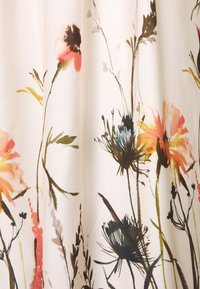 Blommönstrat tyg med mjuk, flödande textur; innehåller gula, rosa och blå blommor mot en ljus, neutral bakgrund.