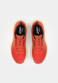 Red athletic shoes with mesh texture, featuring black insoles labeled "ASICS Ortholite," and yellow rubber soles with light blue accents.