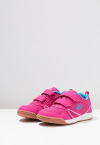 Pink athletic shoes feature a mesh upper with leather accents, dual Velcro straps, and light blue highlights. The sole is rubber with a textured grip.