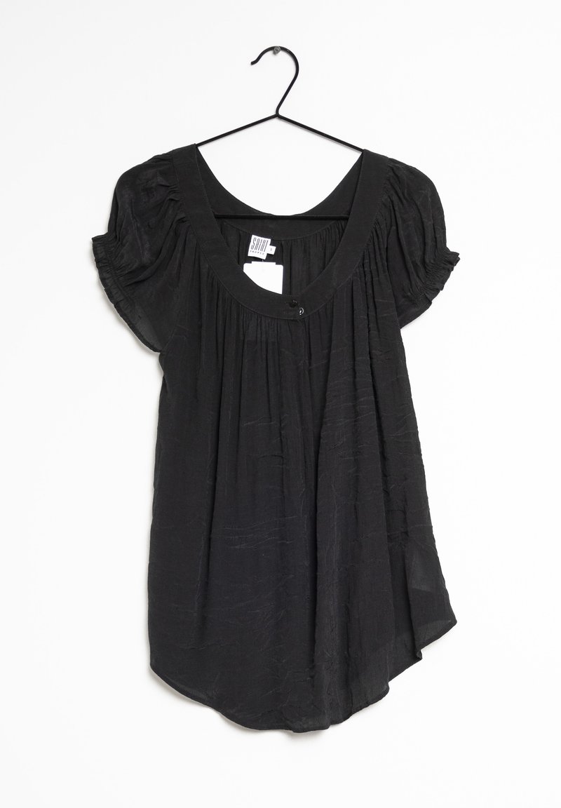 Blouse noire à manches courtes avec encolure dégagée et tissu froncé, suspendue sur un cintre noir sur fond blanc.