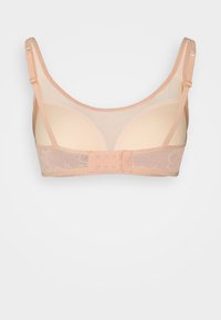 Soutien-gorge en maille beige avec des bonnets moulés et des bretelles réglables. Présente des accents en dentelle et une fermeture à crochets à l'arrière. Matière douce et légère.