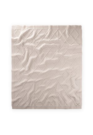 Kremowy dziergany koc z diamentowym wzorem i prążkowanymi krawędziami, rozłożony płasko z drobnymi zagnieceniami i małą metką w rogu.