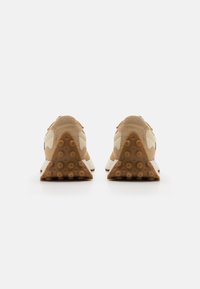 Brune skinnsko og mesh-sneakers med en teksturert gummisåle, som har en trekantet hæl, off-white detaljer og minimal merkevare.