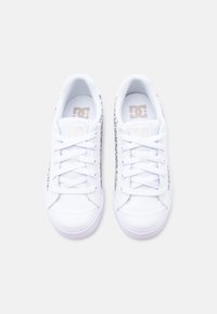 Ζευγάρι λευκών χαμηλών αθλητικών παπουτσιών με κορδόνια και σχέδιο στα πλαϊνά, που φαίνονται από πάνω σε απλό φόντο.