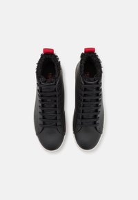 Zwarte high-top sneakers van textuurleer, met een zachte, harige voering en een rode haak. Veters aan de voorkant, witte rubberen zool.