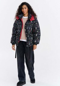Kurtka pikowana z czarnym kwiatowym wzorem, czerwonymi akcentami, wysokim kołnierzem i troczkami. Połączona z luźnymi czarnymi dżinsami i czarnymi butami.