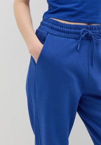 Blauwe katoenen joggers met een elastische tailleband, trekkoord en zakken. Glad textuur met een relaxed fit ontwerp.