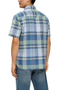 Korte mouwen geruite shirt in blauwe, groene en grijze tinten. Lichtgewicht stof, knoopsluiting bij de kraag en schuin achterpand. Gestyled met denim shorts.