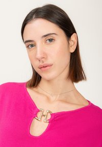 Fuchsia trui met een sleutelgat-halslijn, voorzien van een metallic logo detail met rhinestones. Zachte stof en aansluitend ontwerp.